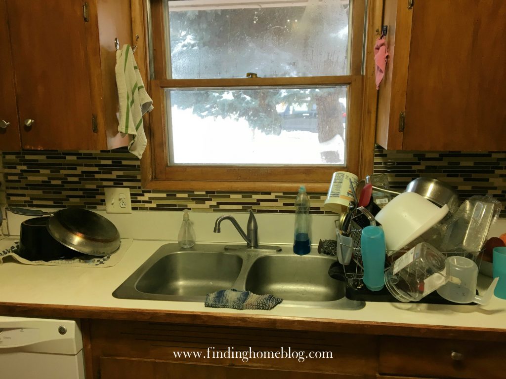 An empty sink, with a rack of clean dishes drying next to it