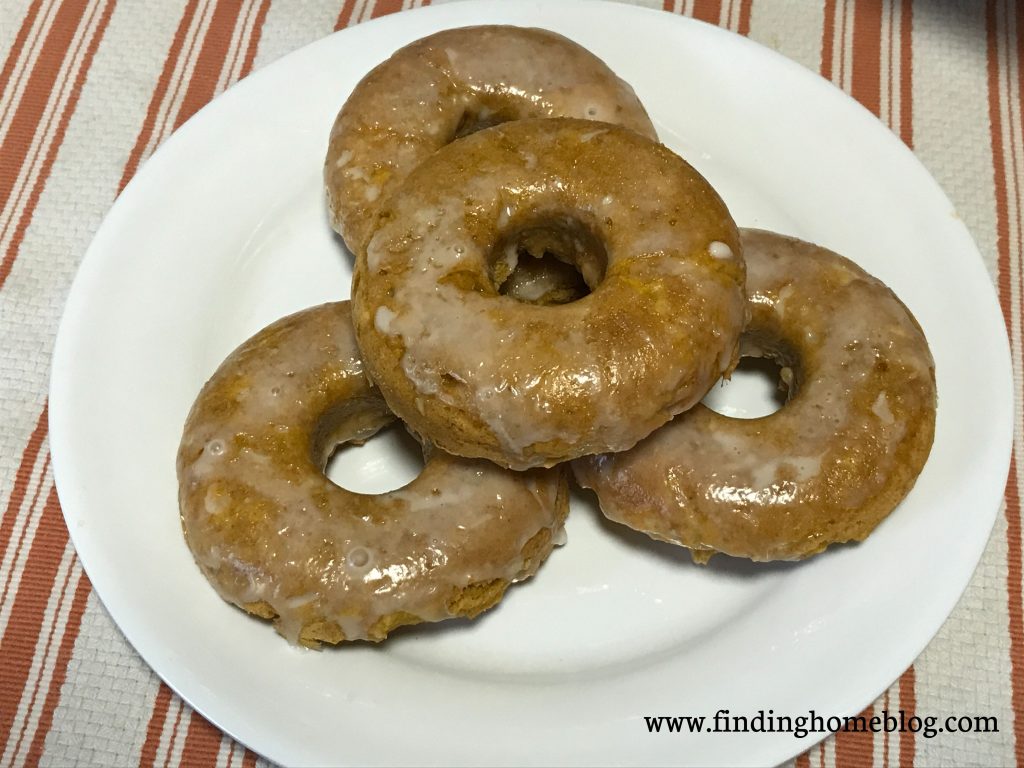 A close-up on a plate of four pumpkin glazed donuts.