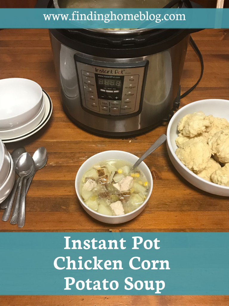 A bowl of soup with a spoon sticking out of it in the middle. Stacks of bowls and spoons to the left. A bowl of biscuits to the right. An instant pot in the background.