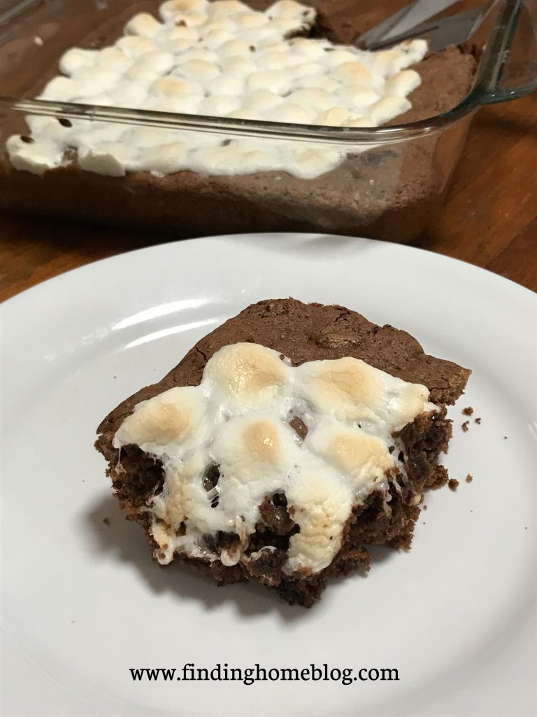 Close up of a brownie topped with slightly browned marshmallows, with the rest of the pan of brownies in the background