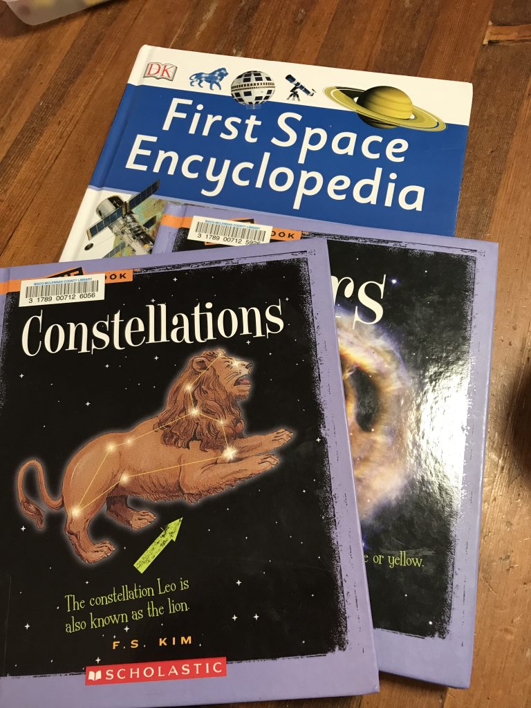 A stack of books about constellations, stars, and space.