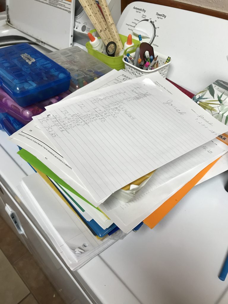 Stack of papers and school books on a dryer.