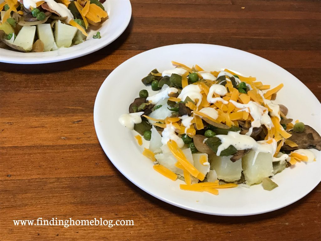 A plate with a baked potato loaded with toppings, including bell peppers, peas, broccoli, and mushrooms, as well as cheese and ranch dressing.
