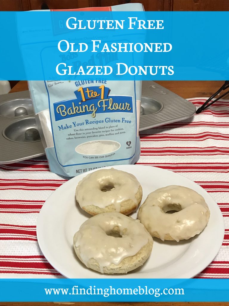 Close up on a plate of three glazed cake donuts. Behind is a package of Bob's Red Mill gluten free 1-to-1 baking flour and a donut pan. A banner across the top reads "Gluten Free Old Fashioned Glazed Donuts"